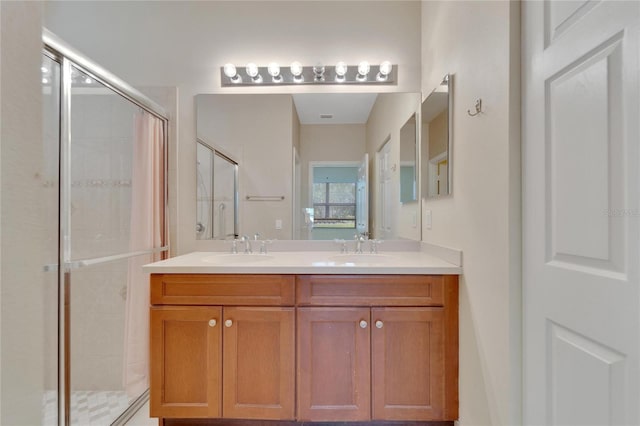 bathroom with a sink, a shower stall, and double vanity