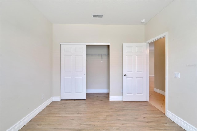 unfurnished bedroom with light wood finished floors, baseboards, visible vents, and a closet