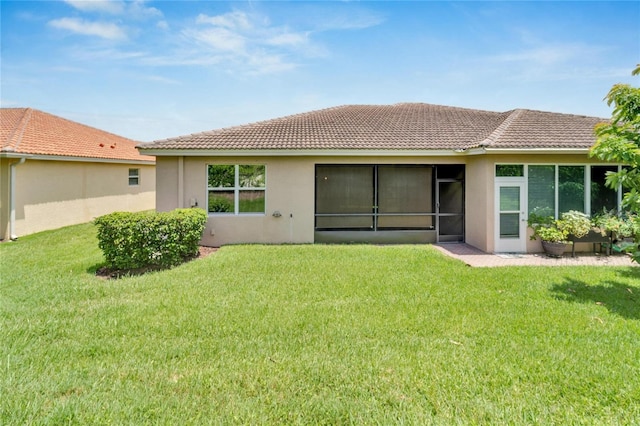 rear view of property with a lawn, a tile roof, and stucco siding