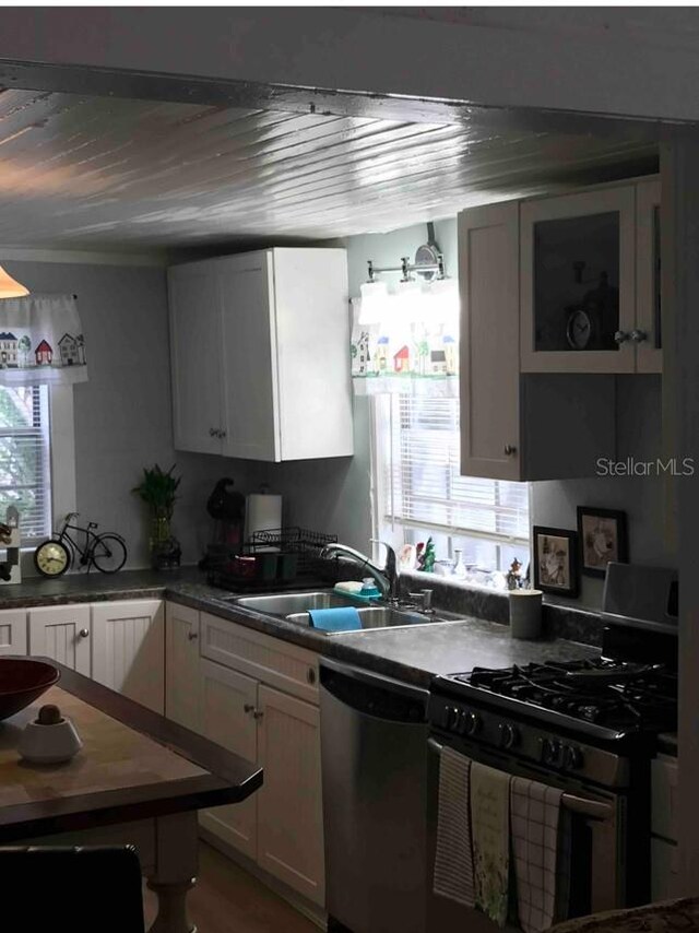 kitchen featuring white cabinets, sink, stainless steel dishwasher, and black range with gas cooktop