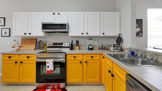 kitchen with appliances with stainless steel finishes, light tile patterned flooring, sink, and a healthy amount of sunlight