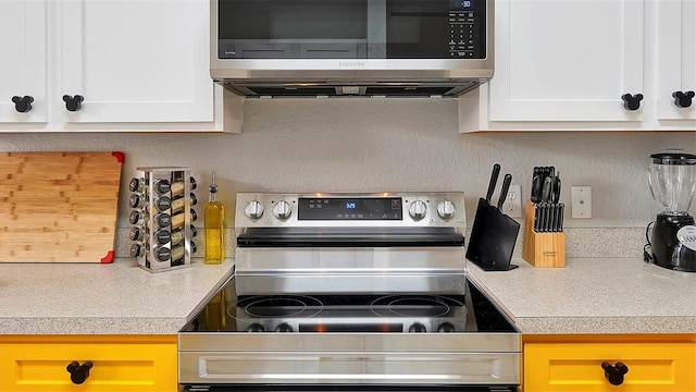 kitchen featuring stainless steel range with electric stovetop and white cabinets