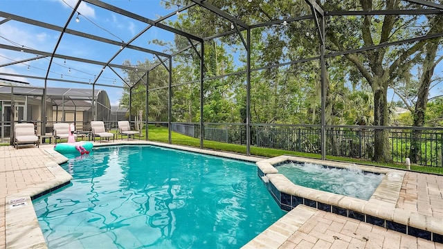 view of pool featuring glass enclosure, a patio, and an in ground hot tub