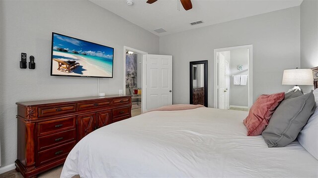 carpeted bedroom with ensuite bath and ceiling fan