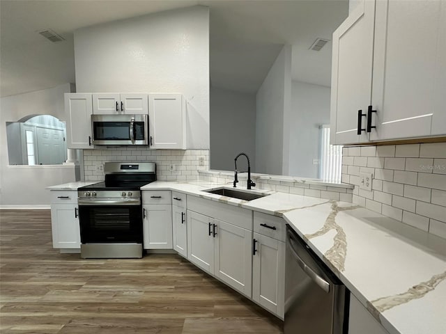 kitchen with appliances with stainless steel finishes, light hardwood / wood-style floors, light stone counters, sink, and white cabinets