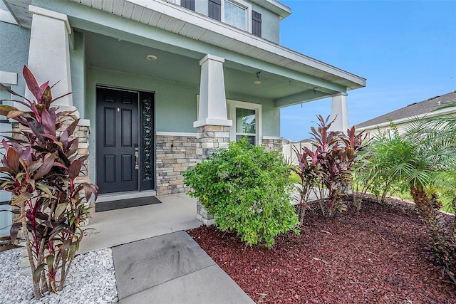 view of exterior entry featuring stone siding and stucco siding