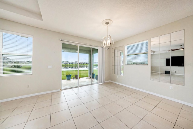 empty room featuring a textured ceiling, a wealth of natural light, and baseboards