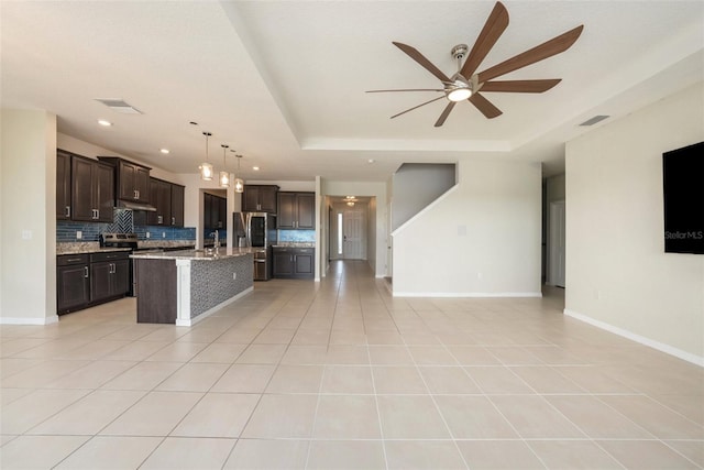 kitchen with open floor plan, a raised ceiling, and stainless steel fridge