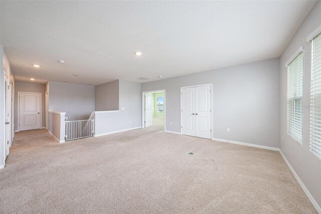 empty room with recessed lighting, baseboards, a textured ceiling, and light colored carpet