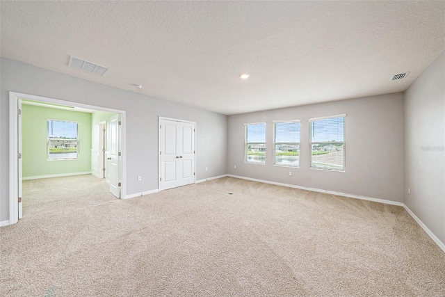 spare room with baseboards, visible vents, and light colored carpet