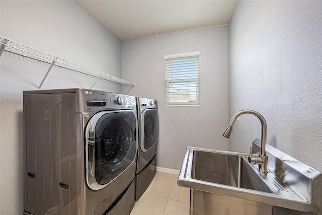 clothes washing area featuring light tile patterned floors, washing machine and dryer, laundry area, a sink, and baseboards