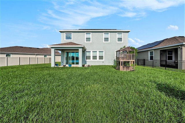 rear view of house with a fenced backyard, a lawn, and stucco siding