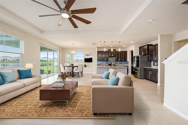 living room featuring light tile patterned floors, a tray ceiling, and baseboards