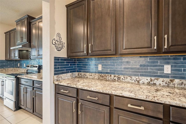 kitchen with light stone counters, stainless steel electric range oven, light tile patterned floors, dark brown cabinets, and under cabinet range hood