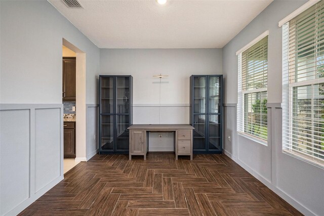 unfurnished office with a wainscoted wall, visible vents, and baseboards