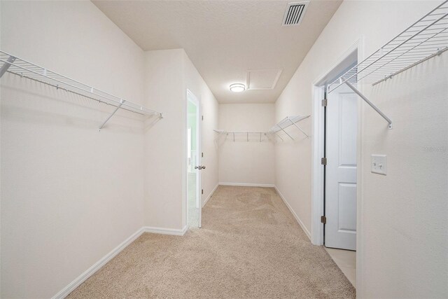 walk in closet featuring attic access, light carpet, and visible vents