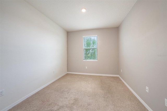 carpeted empty room with a textured ceiling and baseboards