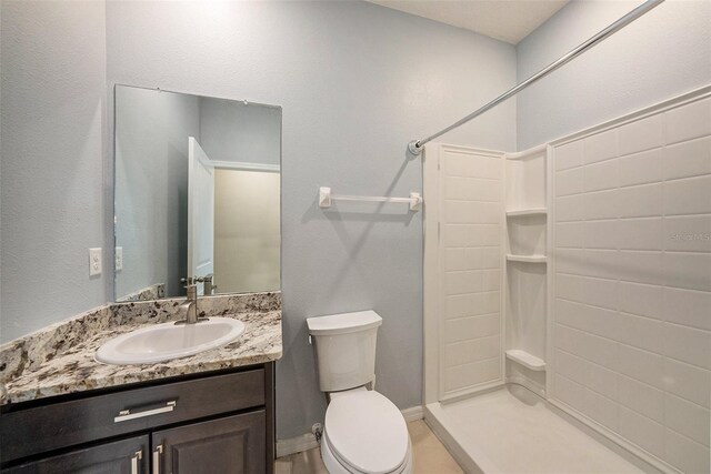 bathroom with a shower, vanity, toilet, and baseboards