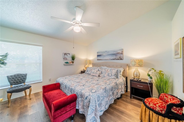 bedroom with ceiling fan, hardwood / wood-style flooring, a textured ceiling, and vaulted ceiling