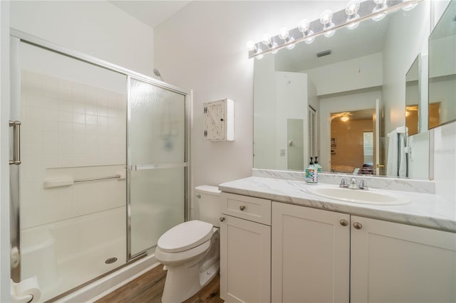 bathroom with an enclosed shower, hardwood / wood-style flooring, vanity, and toilet