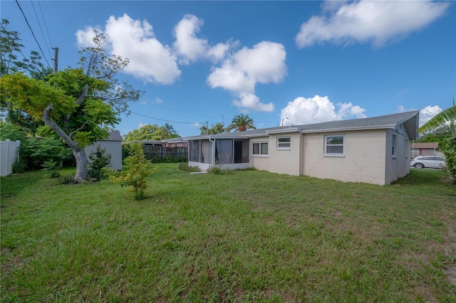 rear view of house with a storage shed and a lawn