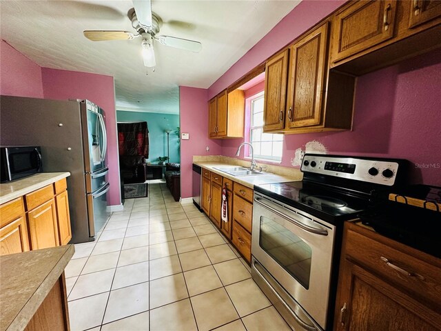 kitchen with appliances with stainless steel finishes, sink, light tile patterned flooring, and ceiling fan