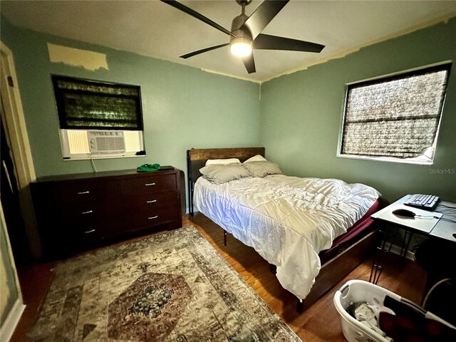 bedroom featuring dark wood-type flooring, cooling unit, and ceiling fan