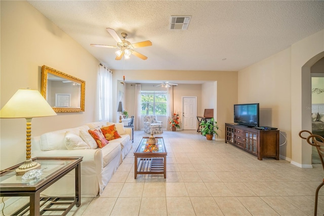 living area featuring arched walkways, visible vents, ceiling fan, a textured ceiling, and tile patterned flooring