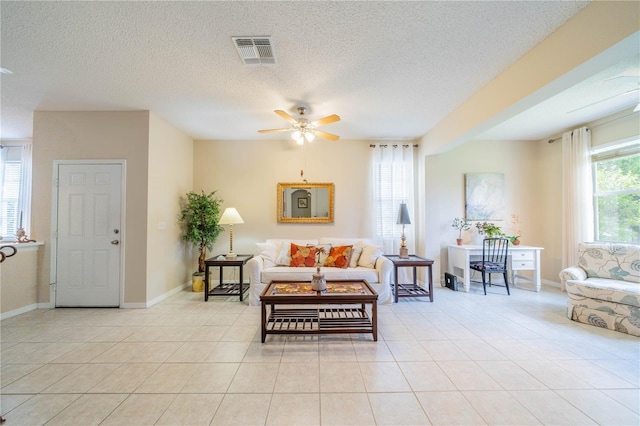 living area featuring ceiling fan, a textured ceiling, light tile patterned flooring, and visible vents