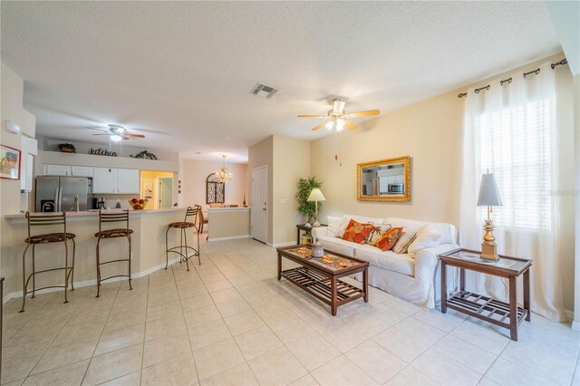 living room featuring a textured ceiling, light tile patterned floors, and ceiling fan