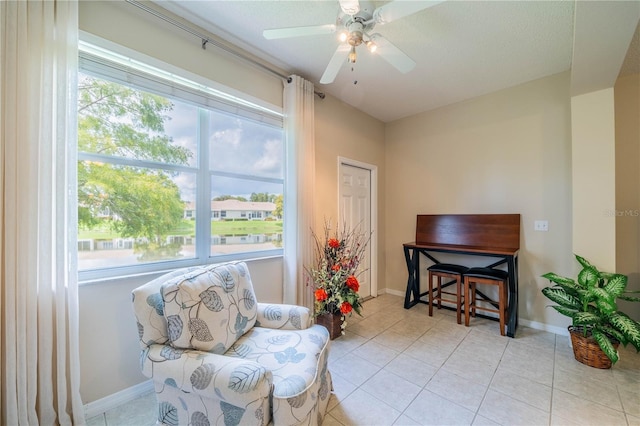 living area with tile patterned flooring, a ceiling fan, and baseboards