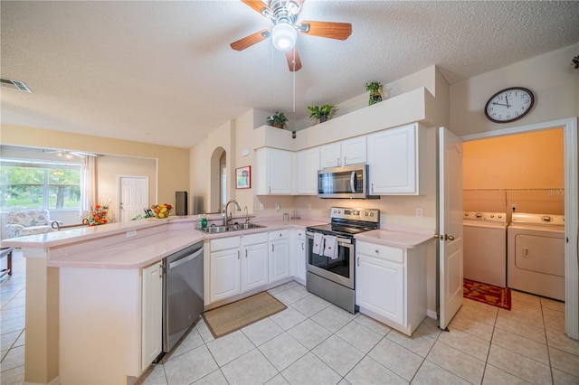 kitchen with appliances with stainless steel finishes, sink, washer and dryer, and kitchen peninsula