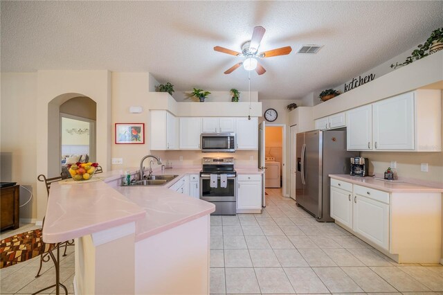 kitchen featuring ceiling fan, kitchen peninsula, light tile patterned flooring, stainless steel appliances, and sink