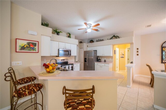 kitchen with white cabinets, light tile patterned flooring, stainless steel appliances, and kitchen peninsula