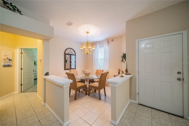 dining area featuring a textured ceiling, a chandelier, light tile patterned flooring, visible vents, and baseboards