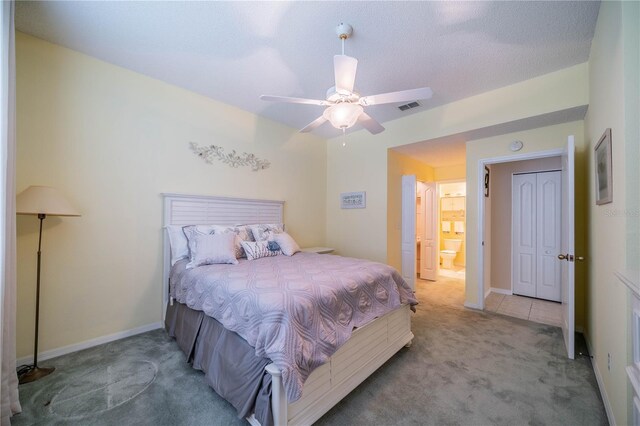 bedroom featuring ceiling fan, connected bathroom, and light colored carpet