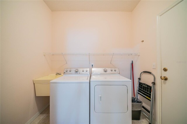 clothes washing area with light tile patterned floors, sink, and washer and dryer