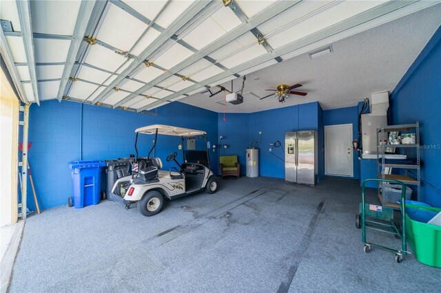 garage featuring ceiling fan, a garage door opener, stainless steel refrigerator with ice dispenser, and water heater