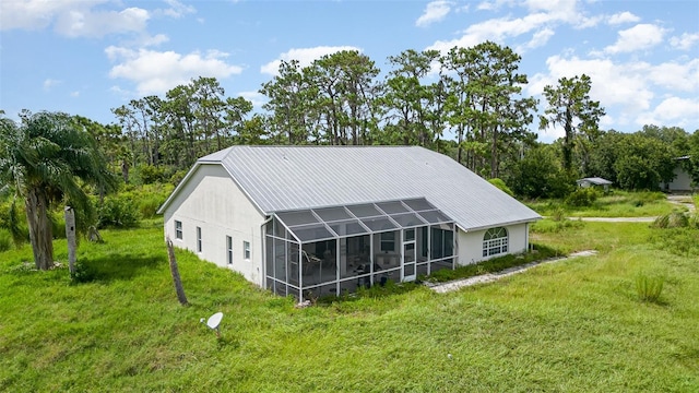 rear view of house with glass enclosure and a lawn