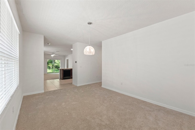 unfurnished room featuring light carpet, light tile patterned floors, baseboards, and a textured ceiling