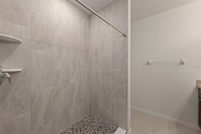 bathroom with tiled shower, vanity, and tile patterned flooring