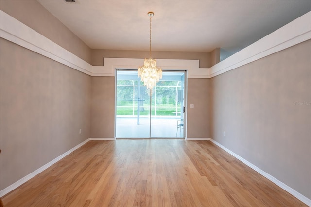 unfurnished dining area with a chandelier and light hardwood / wood-style flooring