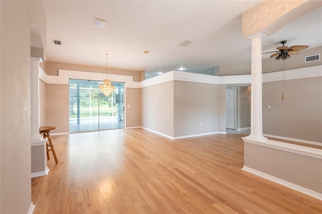 empty room featuring decorative columns, ceiling fan with notable chandelier, and light wood-type flooring