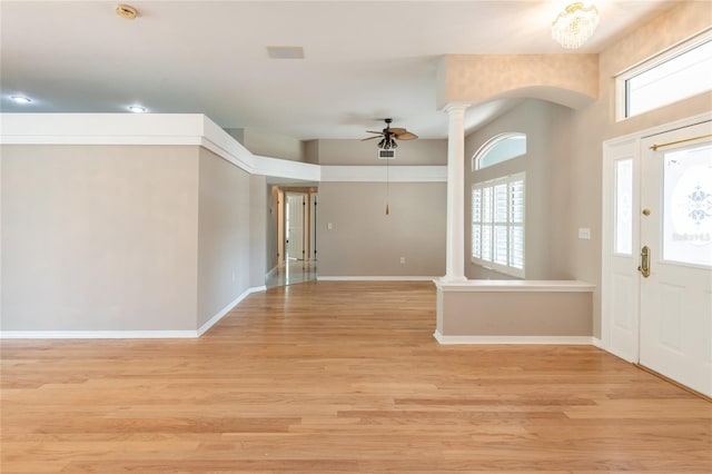 foyer with decorative columns, a wealth of natural light, light hardwood / wood-style floors, and ceiling fan with notable chandelier