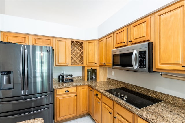 kitchen with light tile patterned floors, dark stone counters, and appliances with stainless steel finishes