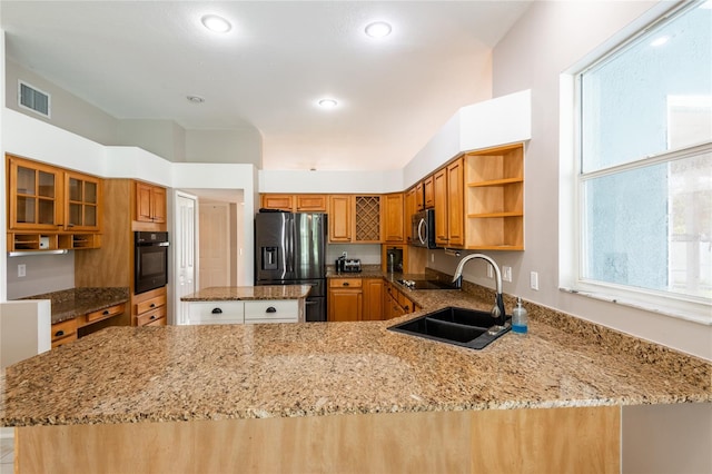 kitchen with kitchen peninsula, stainless steel appliances, light stone counters, and sink