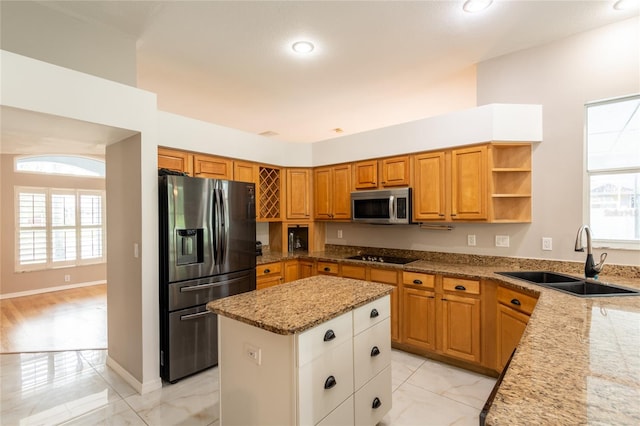 kitchen featuring sink, a center island, a healthy amount of sunlight, stainless steel appliances, and light stone counters