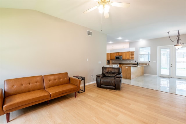 living room featuring french doors, vaulted ceiling, ceiling fan, sink, and light hardwood / wood-style flooring