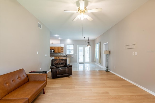 living room with ceiling fan, french doors, and light hardwood / wood-style flooring