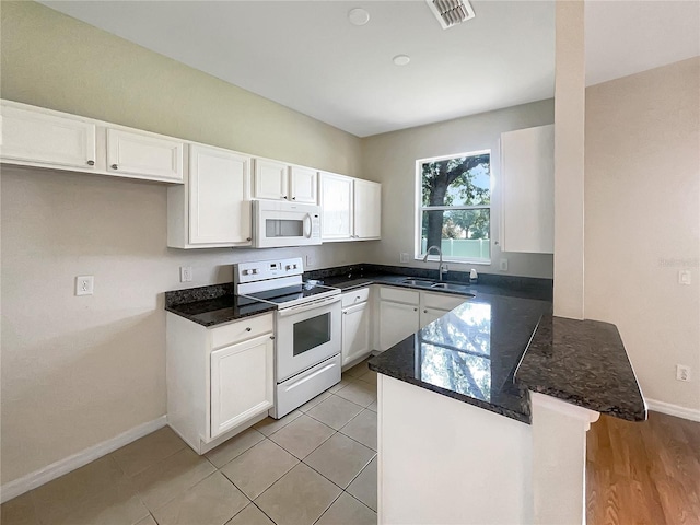 kitchen featuring light hardwood / wood-style flooring, white cabinetry, kitchen peninsula, white appliances, and sink